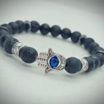 2026/01/1002485378.jpg Pulsera de piedras naturales ónix mate, roca volcánica y dije de mano de Fátima plateado